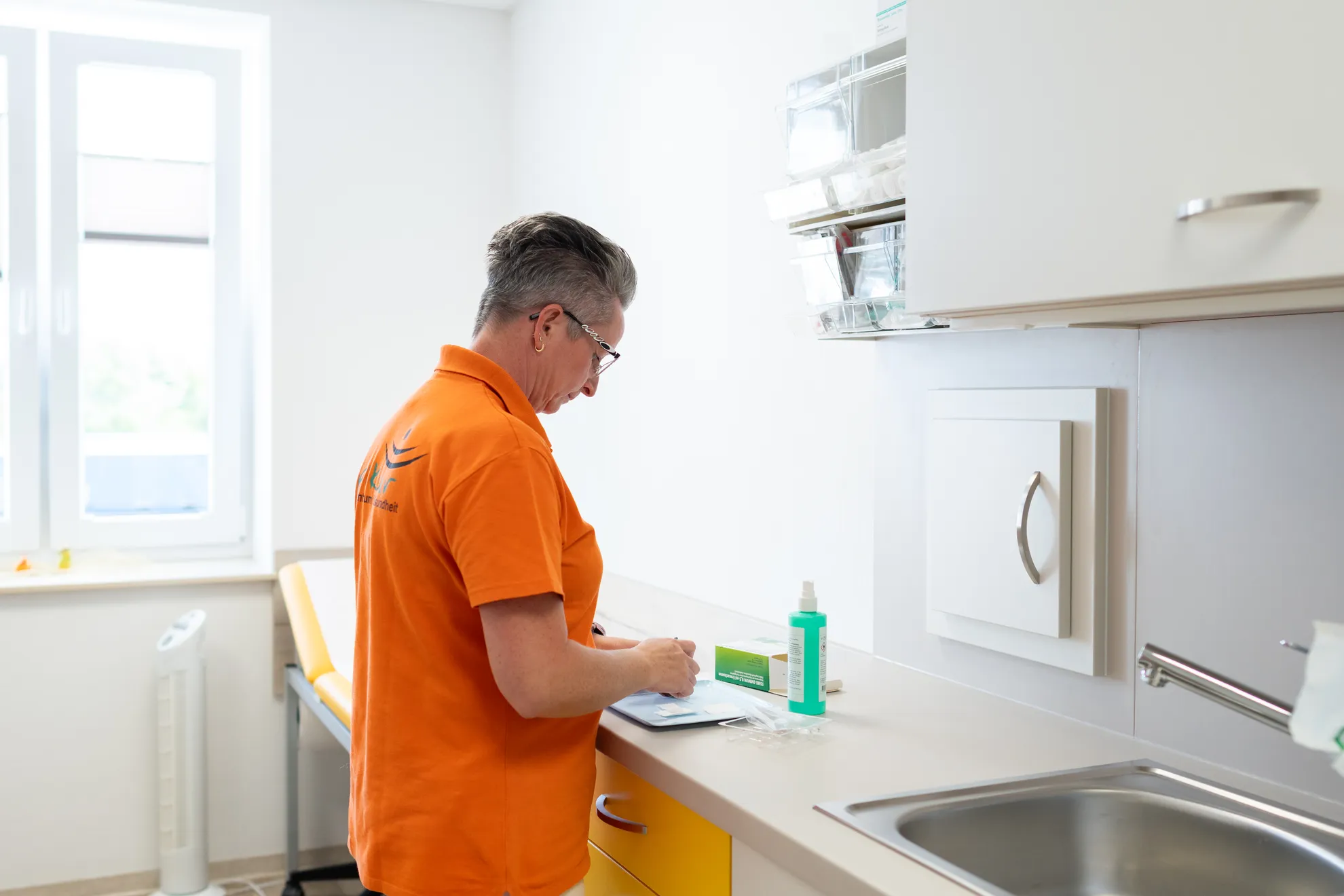 Arzthelferin am Arbeiten mit Desinfektionsmittel und Werkzeugen auf dem Tisch